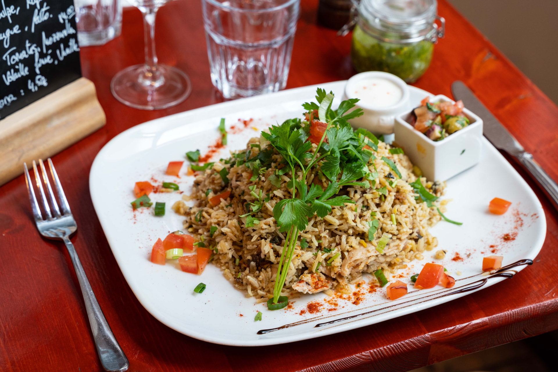 Biryani mauricien au poulet servi avec raita et achard sur une table du restaurant